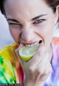 Girl biting into a tangy lemon